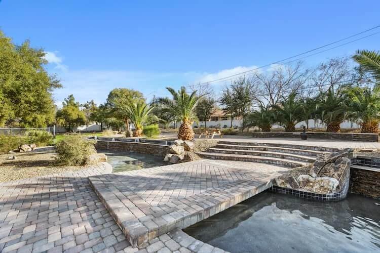 A stone bridge walkway with canal of water that leads to a staircase and palm trees at Desert Hope Treatment Center in Nevada